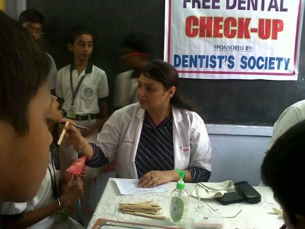 A doctor at a free dental check-up camp, with children around her